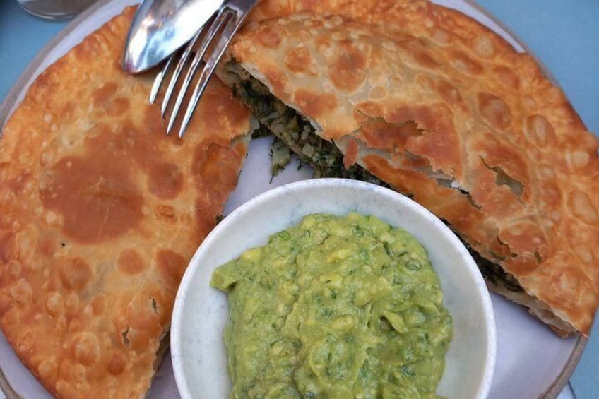 Un plato con un pan plano relleno y un bol de salsa verde. 5