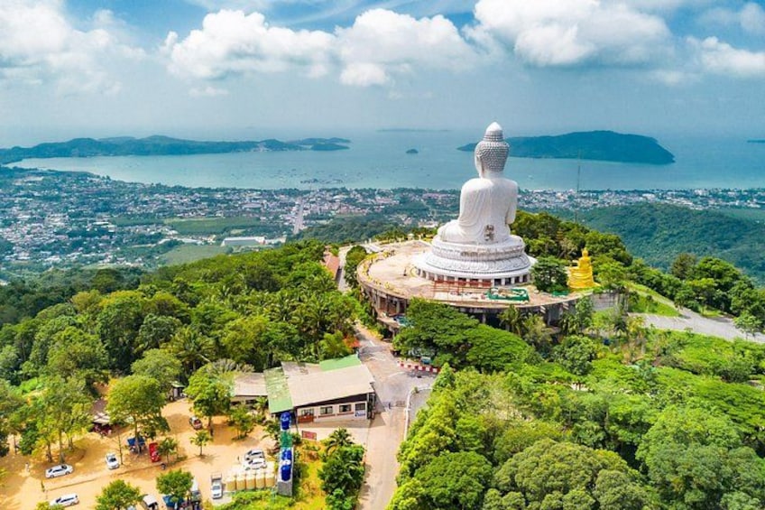 Eine große weiße Statue auf einem Hügel mit Blick auf eine Stadt und ein Gewässer in der Ferne. 2