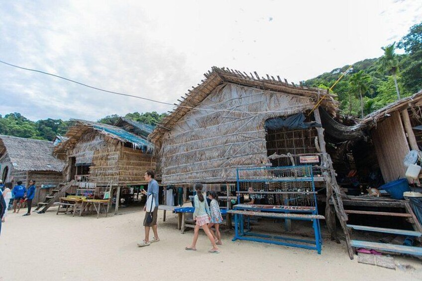 A village with thatched-roof huts, a blue metal structure, and people walking. 5