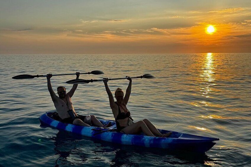 Two people kayaking on a calm body of water during sunset. 3