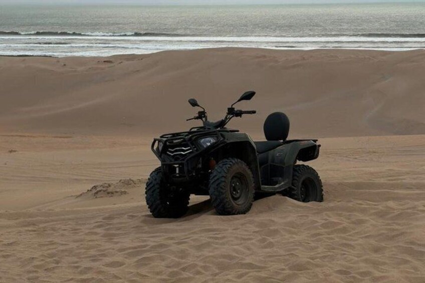 Un quadriciclo parcheggiato su una spiaggia sabbiosa con l'oceano sullo sfondo. 2