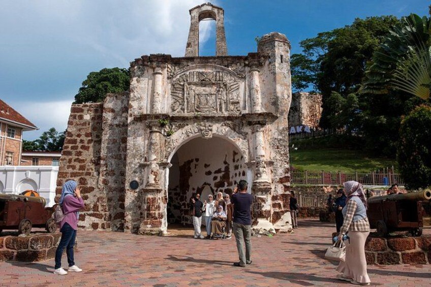 An ancient stone archway with inscriptions, surrounded by tourists. 3