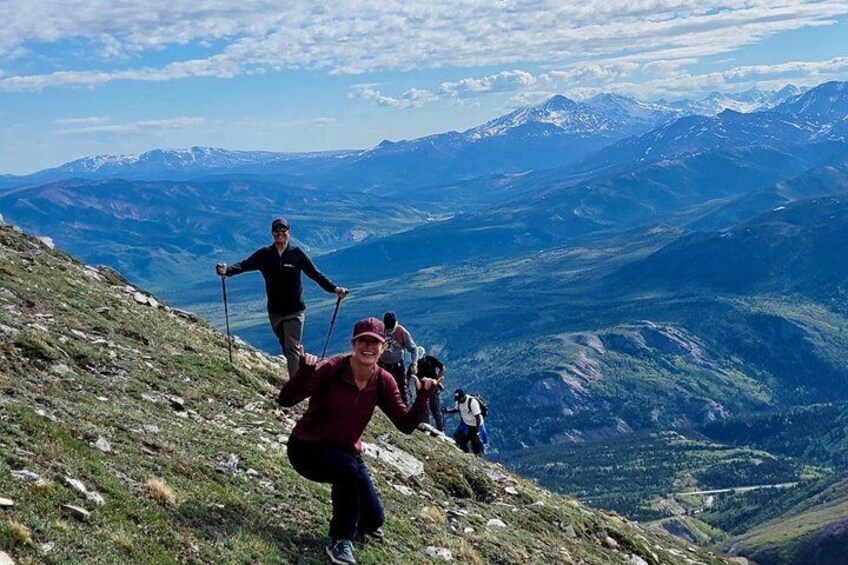 A group of hikers on a mountain trail with a panoramic view of snow-capped mountains and valleys. 5