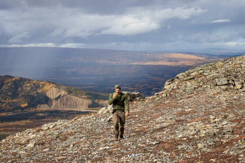A person hiking on a rocky mountain trail with a vast landscape in the background. 2