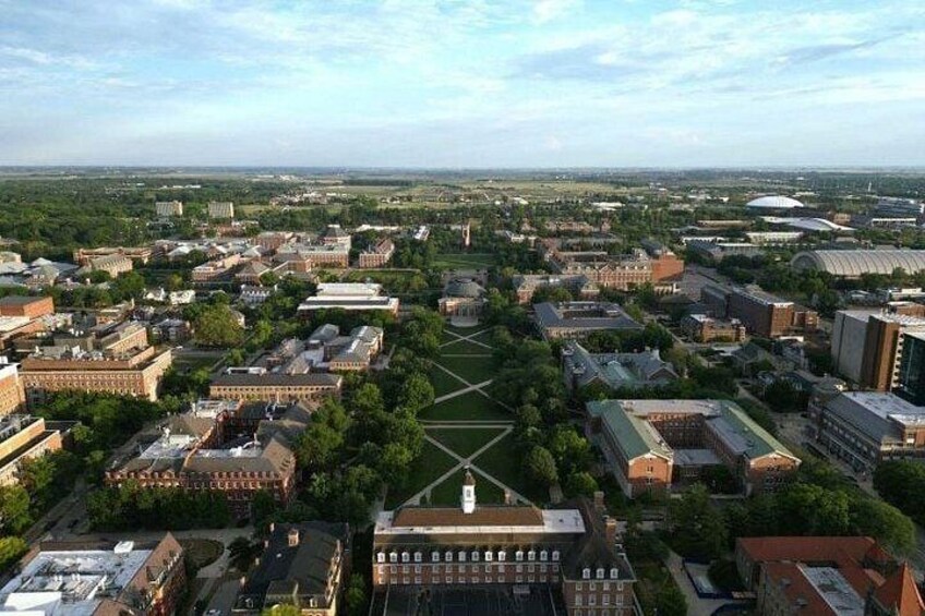 An aerial view of a university campus with multiple buildings, green spaces, and a central quadrangle. 2