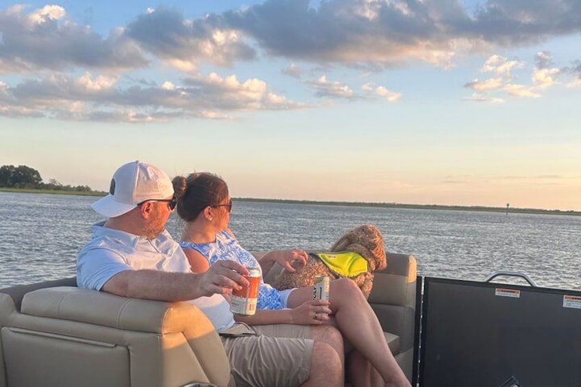 A boat with three people on a calm body of water during sunset. 1