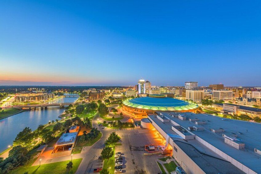 A stadium with a green roof, surrounded by a river, roads, and buildings. 1