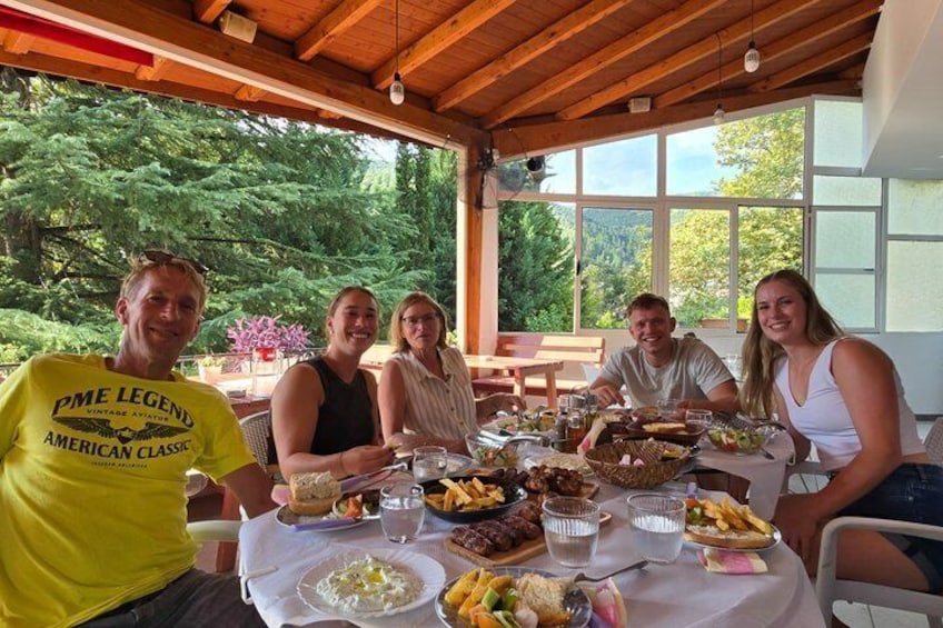 A group of people dining outdoors at a wooden table with various dishes. 2