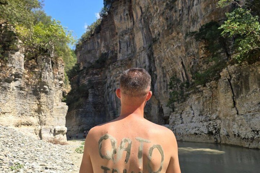 A person standing in front of a rocky cliff with a body of water. 4