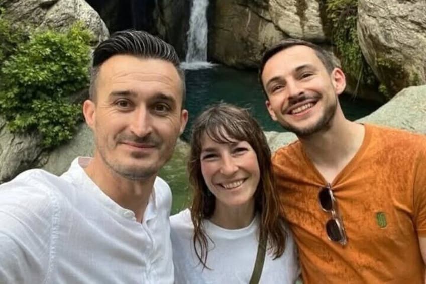 Three people taking a selfie in front of a waterfall. 1