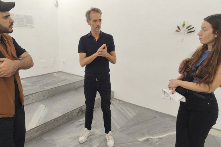Three people in a room with a marble floor and white walls. 3