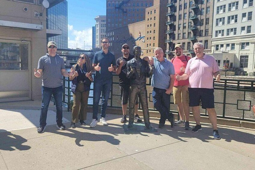 A group of people standing on a bridge with buildings and a river in the background. 2