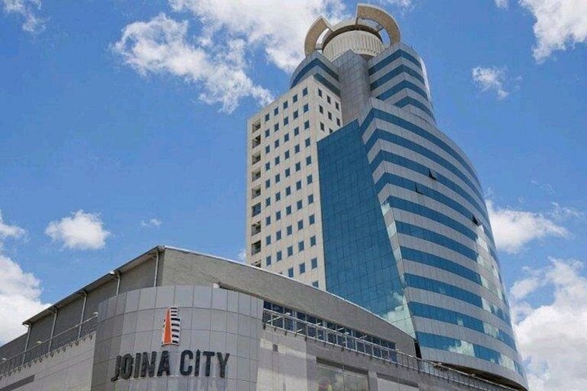 A modern building with a curved facade and a sign that reads 'JOINA CITY'. 5