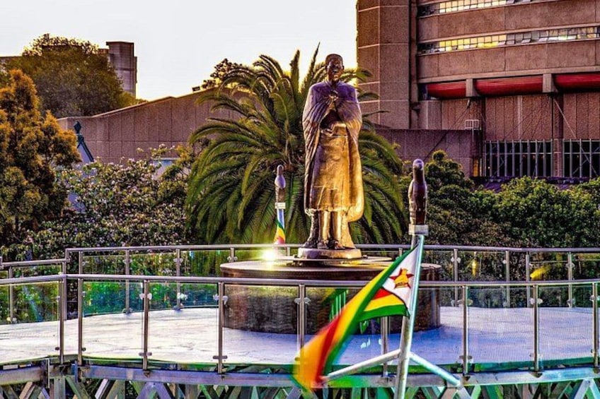 A statue of a historical figure, a flag, and a building in the background. 2