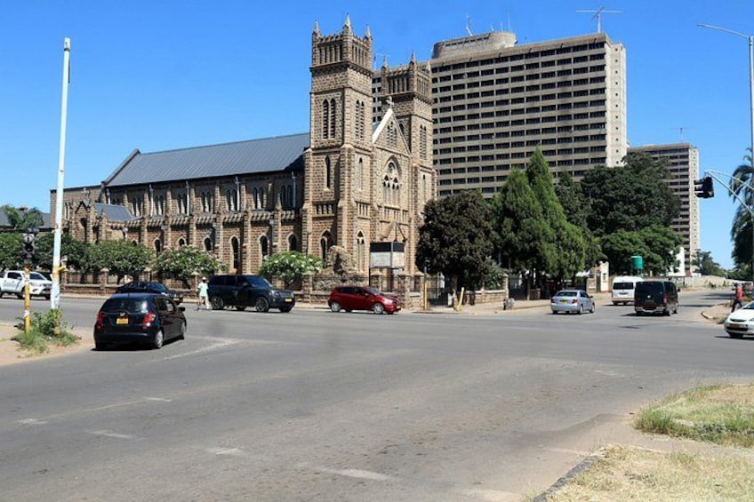 A cathedral with a clock tower, a modern high-rise building, and a busy intersection with cars. 4