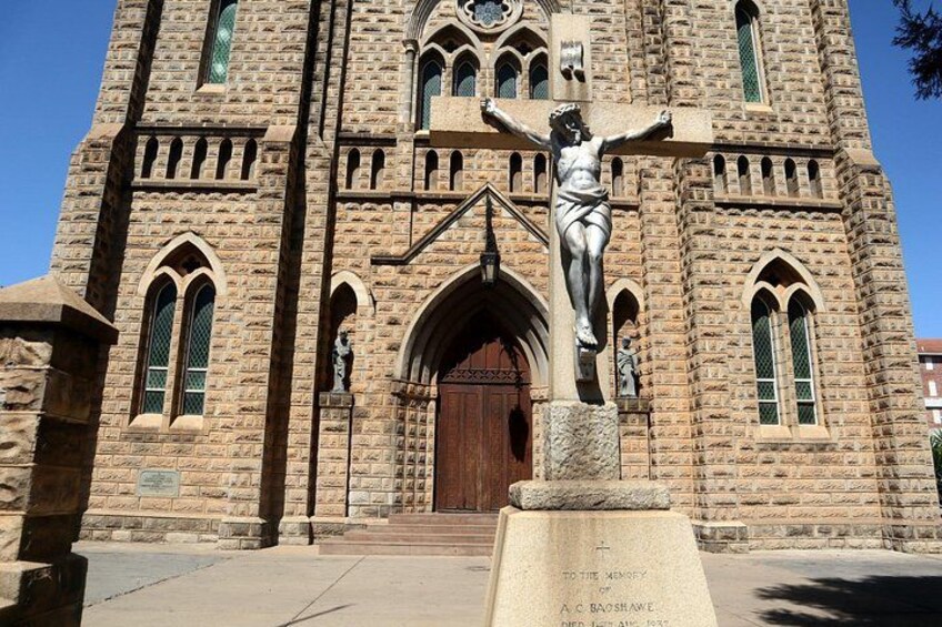 A stone church with a crucifix statue in front. 1