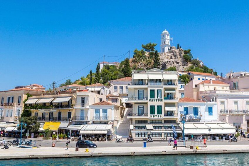 Un pueblo costero con un faro en lo alto de una colina, un hotel y un paseo marítimo. 3