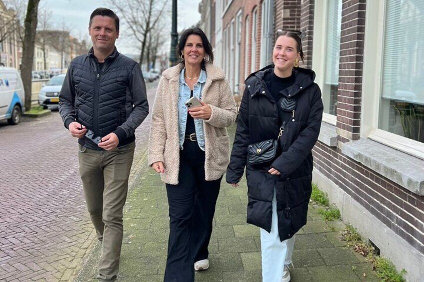 Tre personer går på fortovet, en bygning med vinduer og en parkeret varevogn. 2