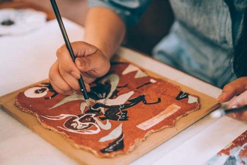A person painting on a wooden board. 3