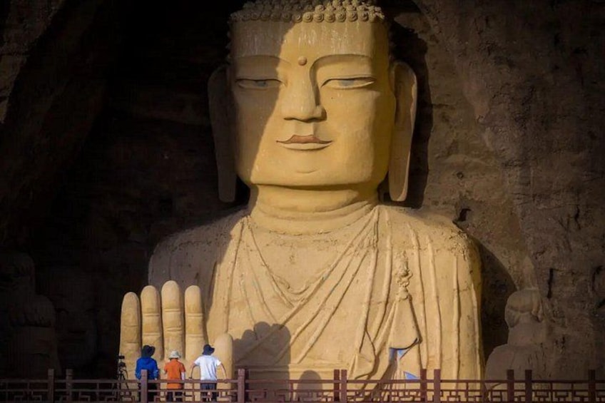 A large Buddha statue with a serene expression, set against a rocky background. 1