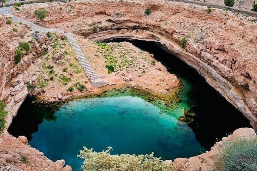 A natural pool surrounded by rocky terrain with a pathway leading to it. 3