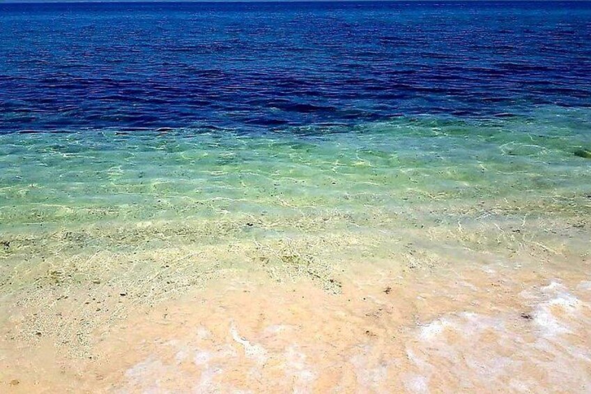 A beach with clear shallow water and a sandy shore. 4