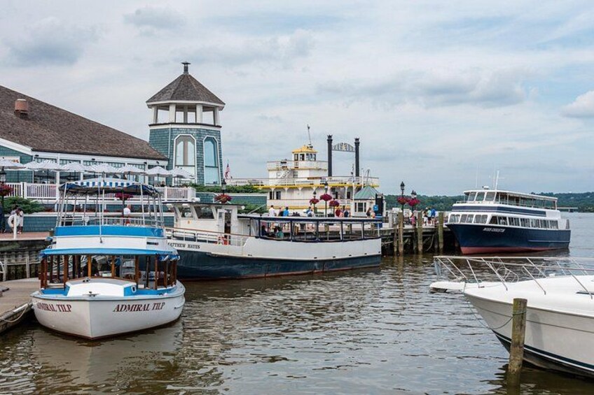 Een haven met verschillende boten afgemeerd, een gebouw met een toren, en een rustig waterlichaam. 2