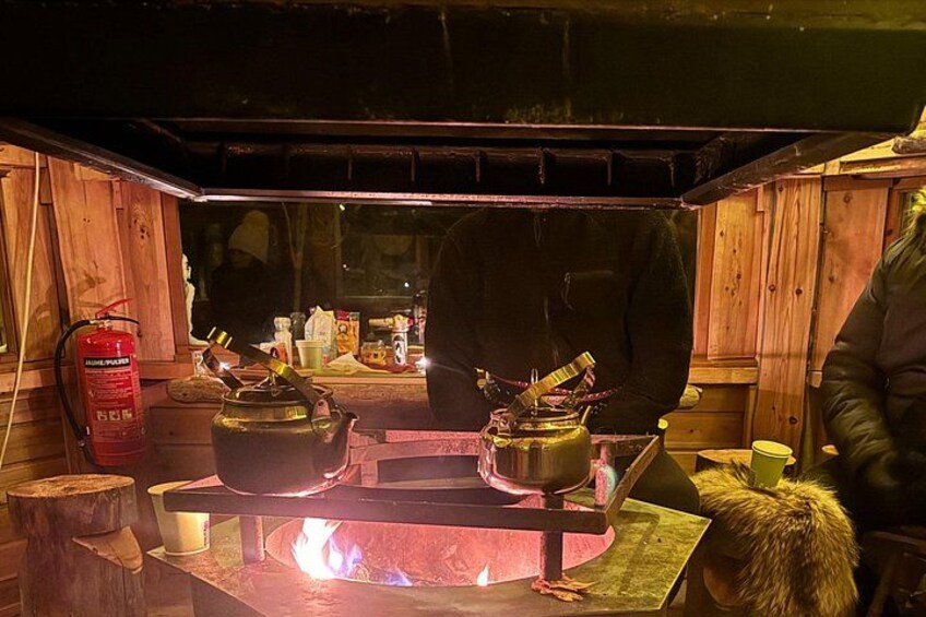 A wood-burning stove with pots and a fire burning. 2