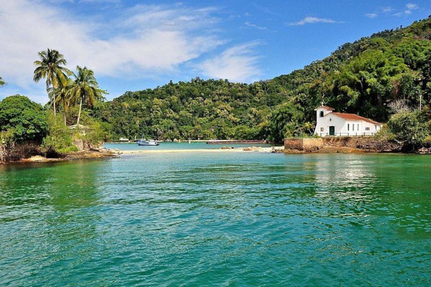 Un paysage côtier avec un bâtiment blanc, des palmiers et une mer d’un bleu limpide. 3