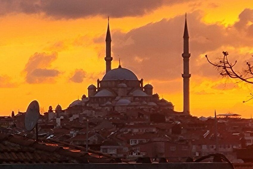 En moské med to minareter og en kuppel mod en solnedgangshimmel. 3