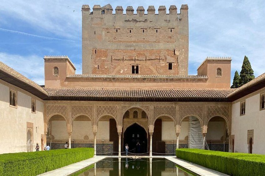 A historic courtyard with a central fountain, arches, and a large tower. 3
