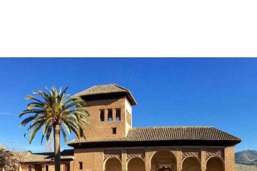 A building with a tiled roof and arches, a palm tree, and a clear blue sky. 5