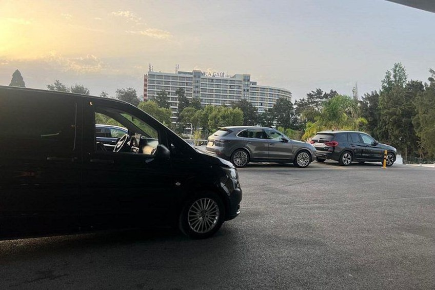 En parkeringsplads med en sort bil i forgrunden og en bygning med 'MILA GATE' i baggrunden. 4