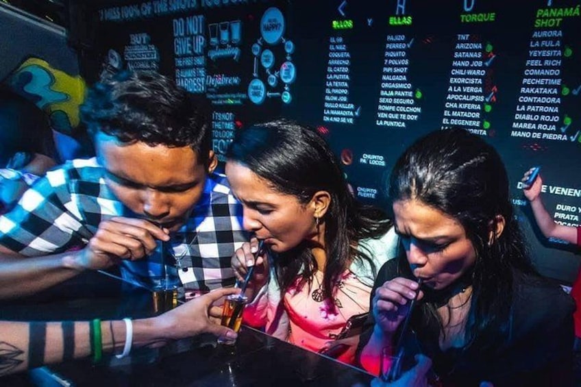 Un bar con gente bebiendo y un panel con varias opciones de bebidas. 1
