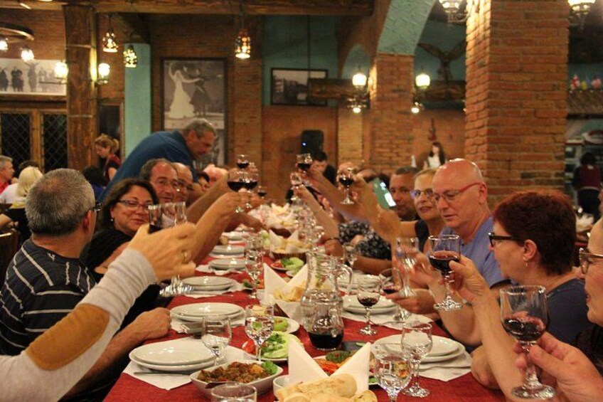 A group of people toasting at a long dining table in a restaurant with brick walls and hanging lights. 5