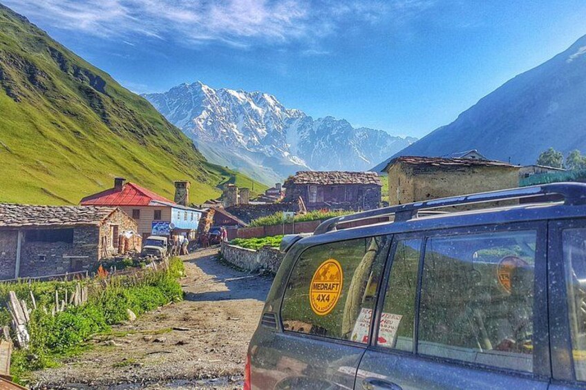 A mountainous village with houses, a road, and a car. 1