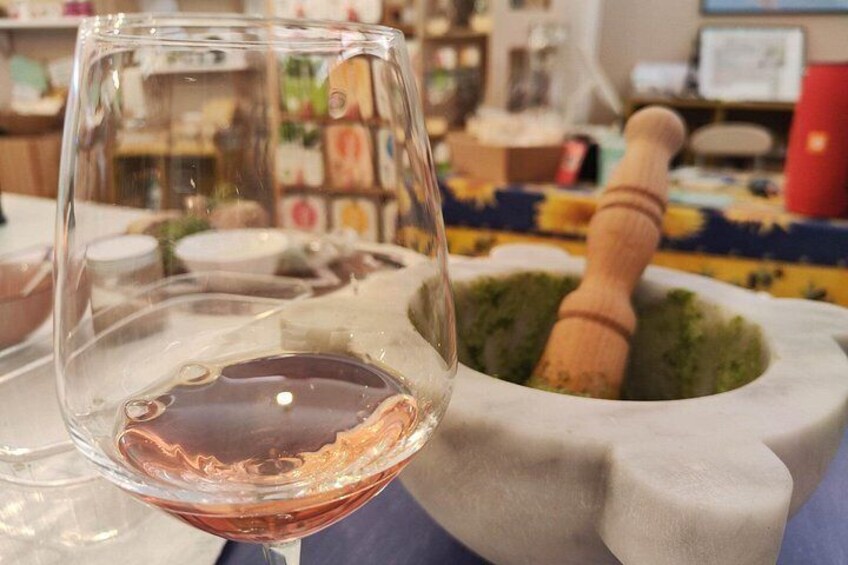 Un verre à vin contenant un liquide rose, un mortier et un pilon, et une nappe colorée. 1