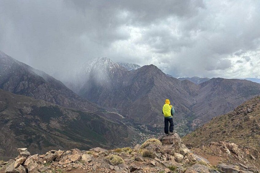 Une personne se tient sur un promontoire rocheux, d’où elle domine un paysage montagneux avec une vallée en contrebas. 3