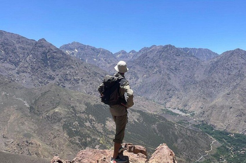 Une personne se tient debout sur un promontoire rocheux, d’où elle domine un paysage montagneux. 4
