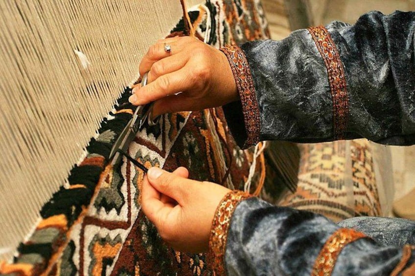 Hands weaving a patterned fabric. 1