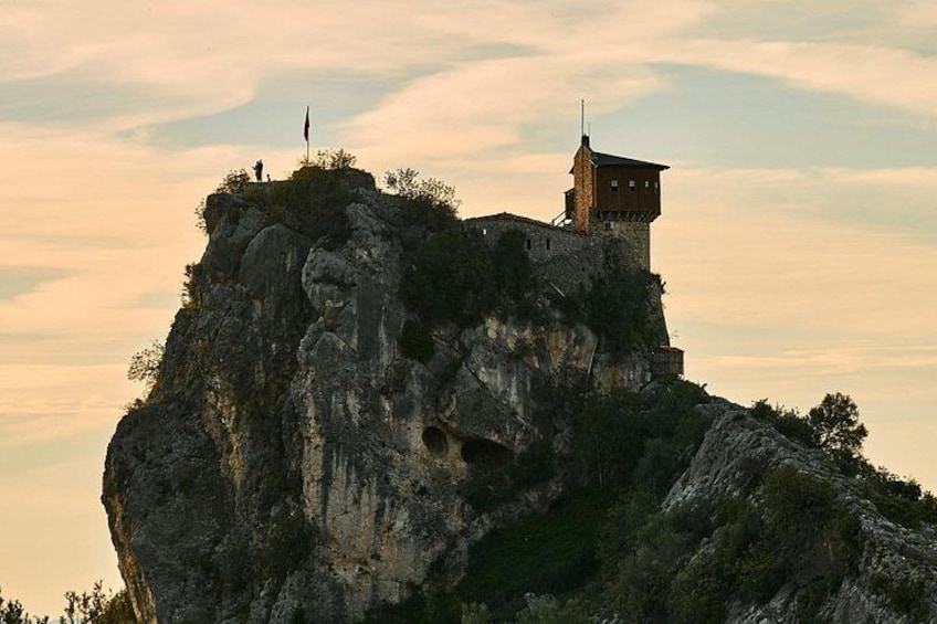 A rocky cliff with a small building on top, surrounded by trees. 2