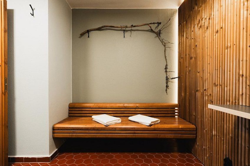 A wooden bench with towels, a branch decoration, and a tiled floor. 5
