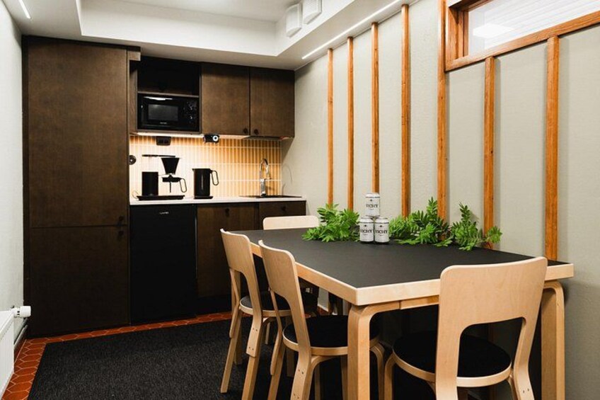 A compact kitchen with dark cabinets, a microwave, a coffee maker, and a dining table with chairs. 4