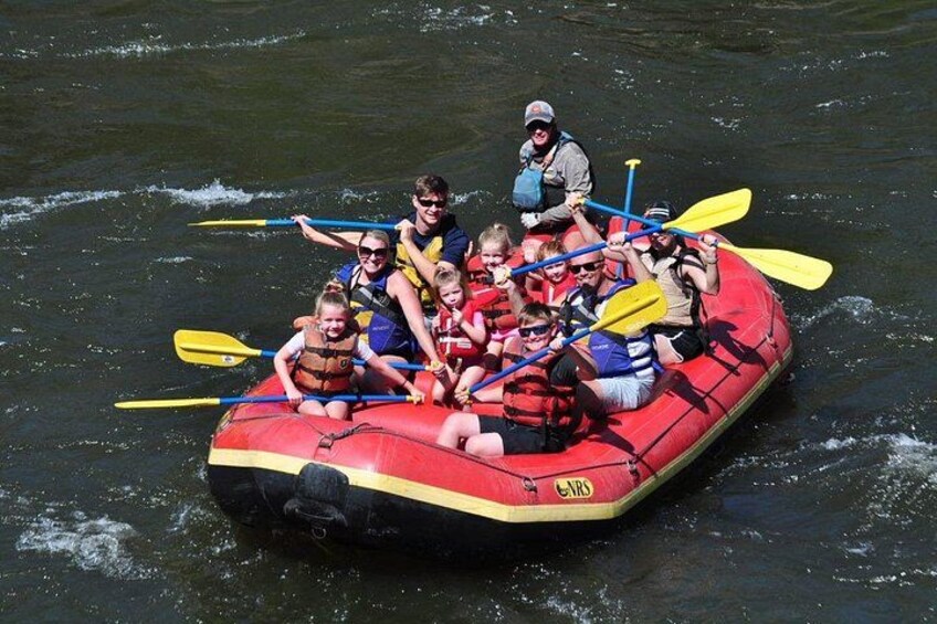 A group of people in a red inflatable raft on a body of water. 4