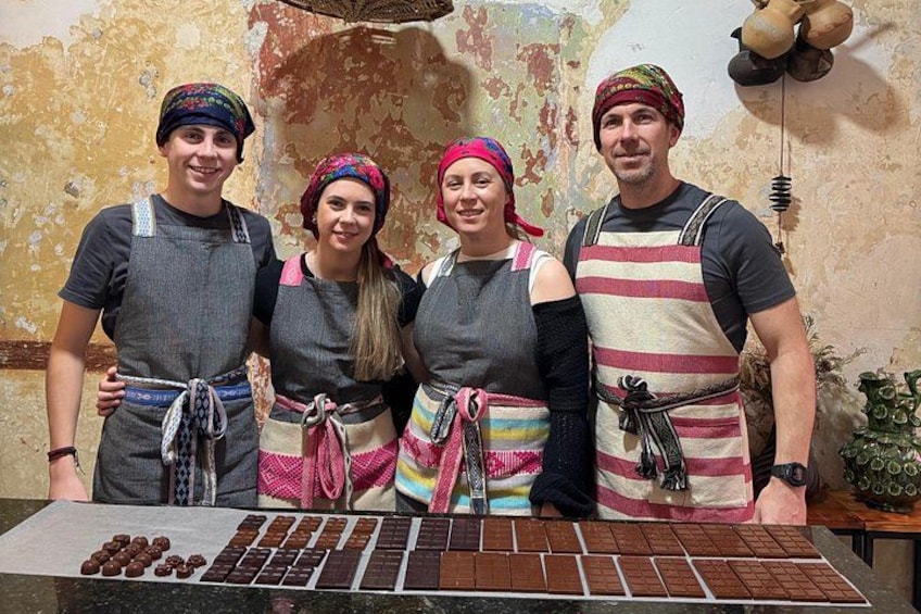 Vier personen staan voor een chocoladepresentatie met een rustieke achtergrond. 1