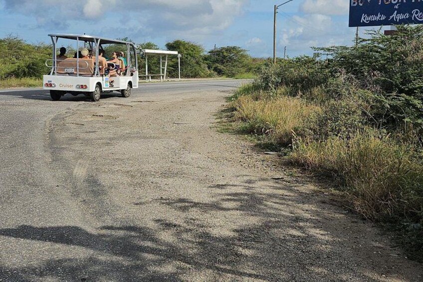 A white vehicle with passengers on a rural road. 5