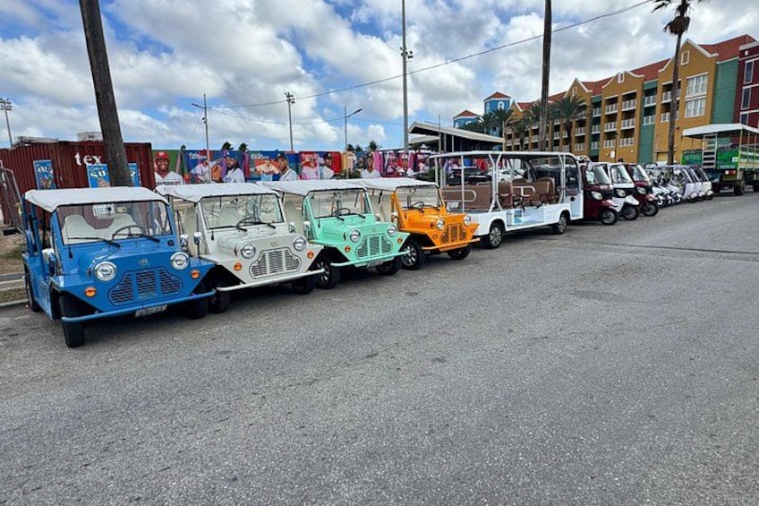 A row of colorful vintage cars parked on a street. 2