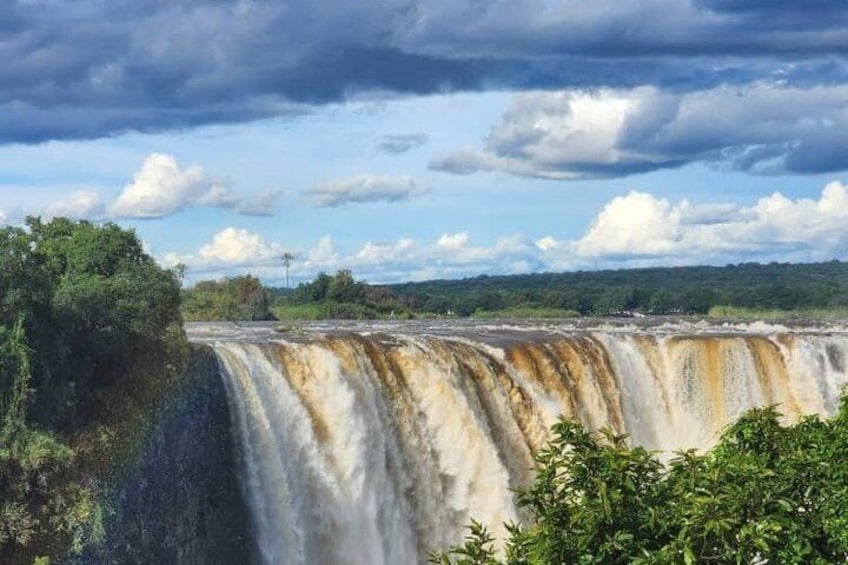 Une grande cascade, avec une zone boisée au premier plan et un ciel nuageux au-dessus. 4