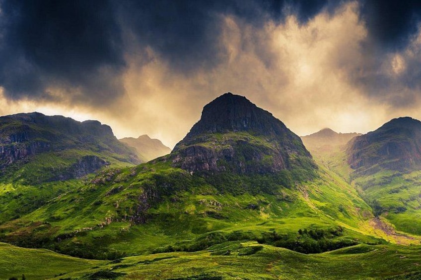 Un paisaje montañoso con colinas verdes y un cielo dramático. 4