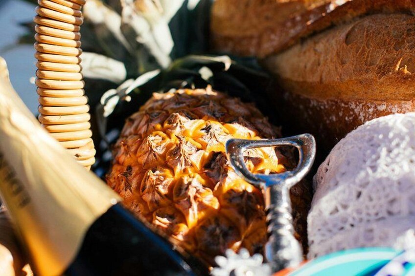 Un ananas, un couteau à découper en métal, une miche de pain et un panier en osier. 1